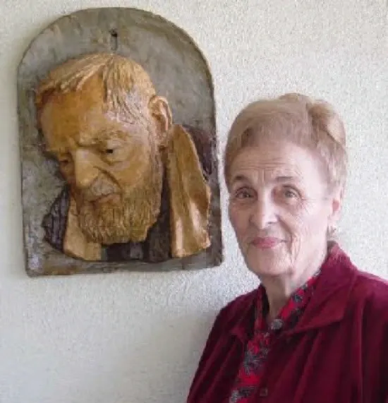 Woman standing beside a carved wall sculpture.