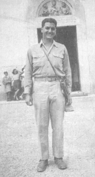 Soldier posed outside building entrance.