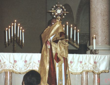 A priest in gold robes standing next to candles.