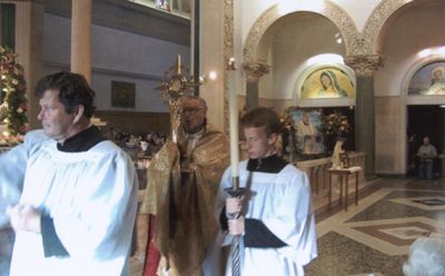 A priest and two boys in white robes
