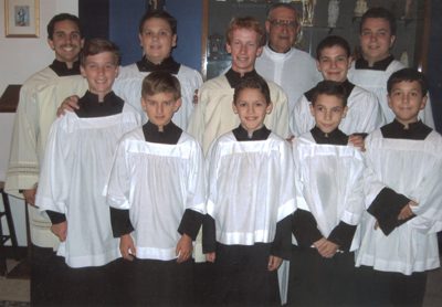A group of young men in white robes and black shirts.