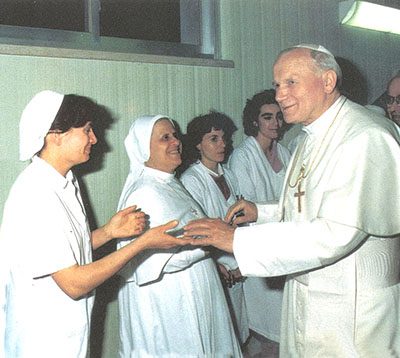 A group of nuns and an older man in white robes.