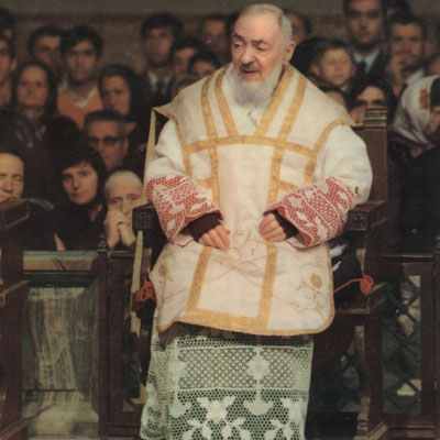 A man in white robe and beard standing next to crowd.