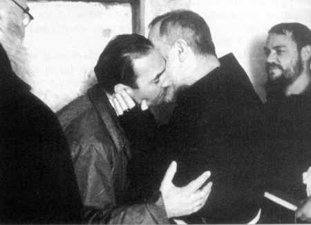 Two men kissing each other in a room.