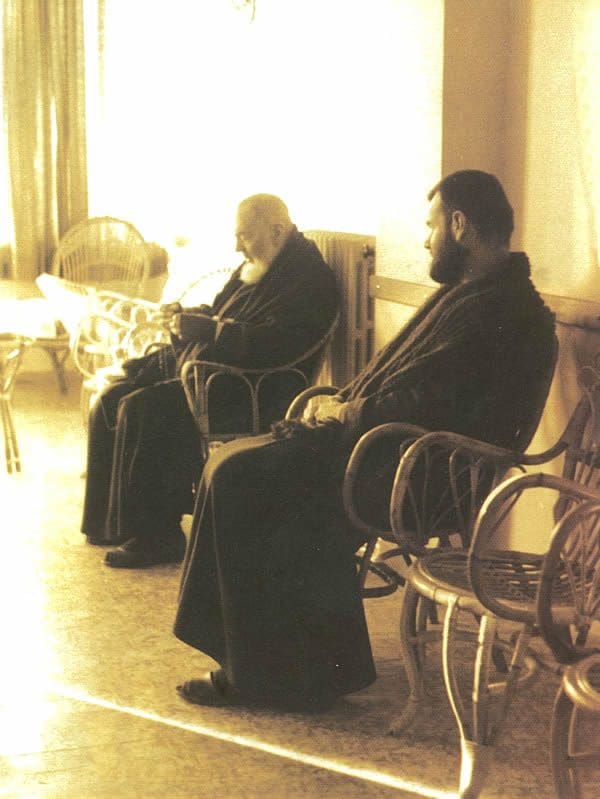 Two men sitting on a bench in front of a window.