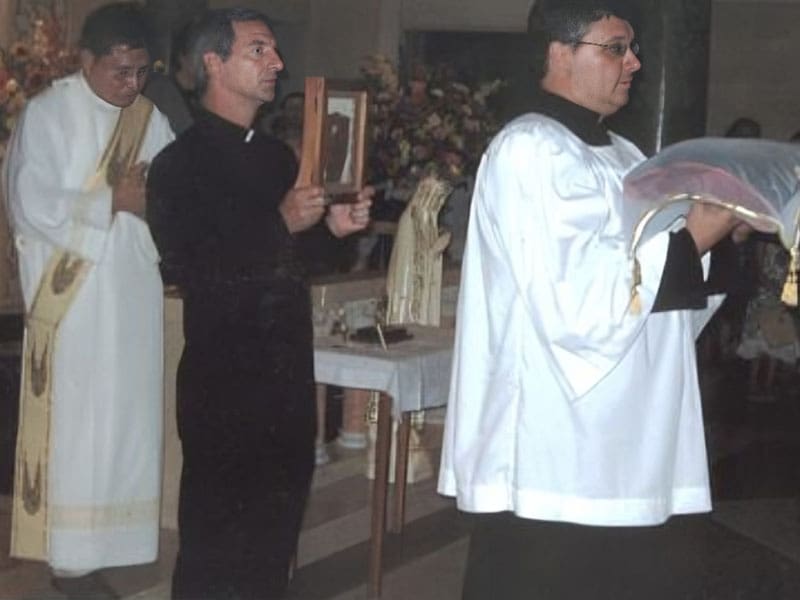 Two men in black and white robes holding wooden utensils.