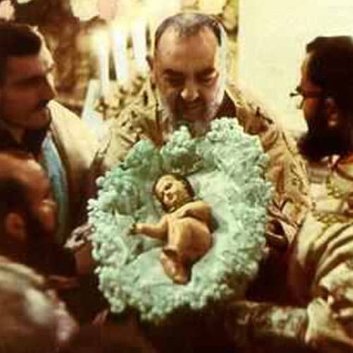 A man holding a baby in a wreath of flowers.