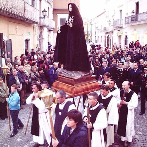 A group of people in the street with a statue.