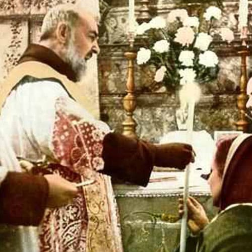 A priest is holding the hand of an older woman.