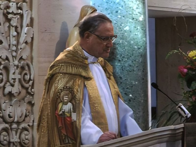 A man in a gold and white outfit standing at the podium.