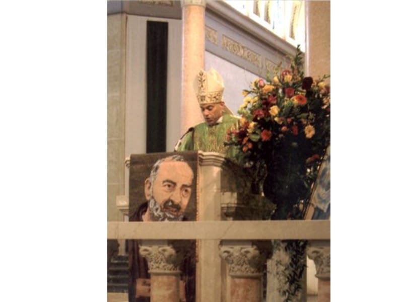 A man in green shirt standing next to a statue.