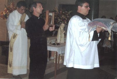 A priest is holding his hands up in prayer.