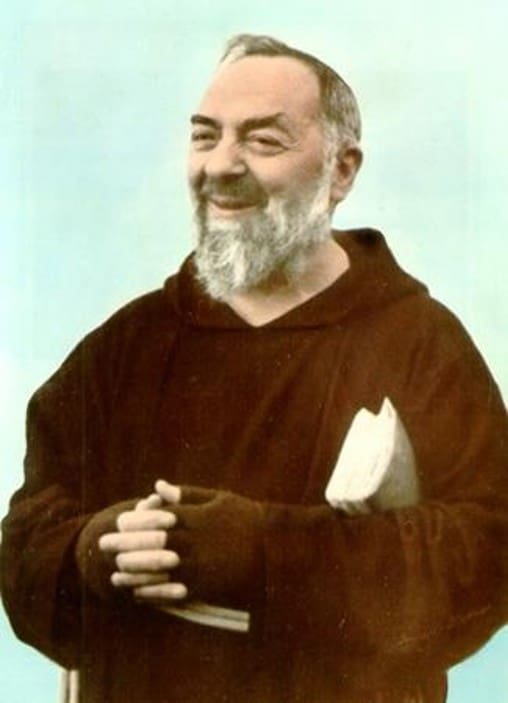 Smiling friar in brown robe holding book.