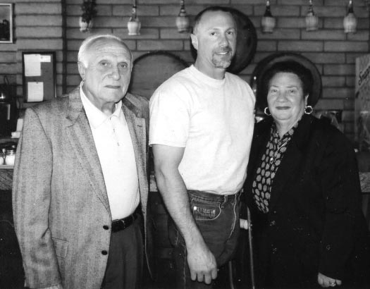 Three people posing in a restaurant setting.